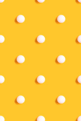 Wall Mural - Pattern made of white ping pong ball on a bright yellow background. Creative layout.