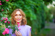 © Igor Borodin - Beautiful successful middle aged woman smelling bloom roses and enjoying in garden outdoors.