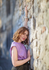 Wall Mural - Beautiful successful middle aged woman posing against a stone wall street, photo shoot