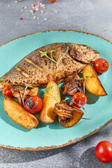 Canvas Print - Close-up of grilled Dorada fish, perfectly cooked with potatoes, mushrooms, and cherry tomatoes. Served on a blue ceramic plate, it offers a feast for the eyes and palate