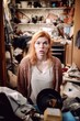 © stickerside - shot of a woman looking confused while standing inside her messy house