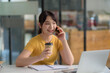 © amnaj - Casual City Lifestyle. Pretty Asian woman talking on the phone and holding coffee.