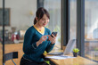 © amnaj - Young Asian Woman Enjoying Smartphone in Trendy Coffee Shop