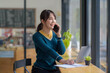© amnaj - Young Asian woman talking on the phone in a coffee shop.