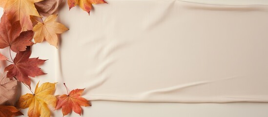 Poster - Autumn composition with maple leaves and beige fabric on a isolated pastel background Copy space Minimalist style top view