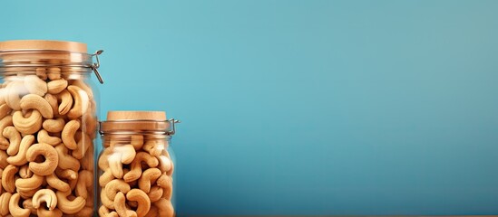 Wall Mural - Fried cashews in glass jars with top view on a isolated pastel background Copy space