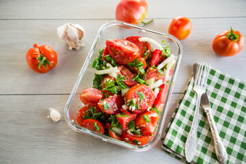 Wall Mural - Spicy snack tomatoes with garlic, herbs, seasonings and onions in a glass bowl .