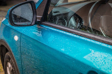 Poster - Raindrops on the car. Car element with raindrops close-up. Doors, mirror and glass of a blue car in raindrops. Big raindrops on the car very close