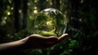 A person holding a glass ball with a forest inside of it