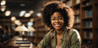 Bellissima ragazza di origini africane con capelli ricci e occhiali studia in biblioteca