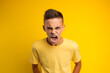 © Mihai Zaharia - Studio portrait of a teenager boy being angry and yelling, isolated on colorful background. Teenager emotions or moods concept. Generative AI