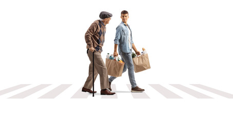 Wall Mural - Elderly man walking with a cane and a young man carrying his grocery bags at a pedestrian crosswalk
