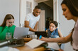 © Maskot - Young man studying with female friends at home