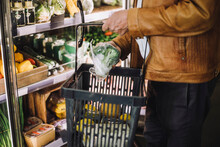Midsection Of Senior Man Buying Organic Broccoli At Grocery Store