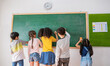 © paulaphoto - Portrait of asian young boy girl writing on blackboard with international classmate at elementary school. Little cute children having classroom activities. Back to school concept