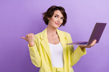 Wall Mural - Photo of attractive young girl wear yellow lime suit holding laptop point finger empty space advertise isolated on violet color background