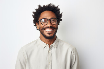 A joyful portrait of a Black man in glasses against a white backdrop.