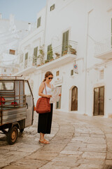 Wall Mural - Female tourist with paper city map on narrow streets of Ostuni, Italy