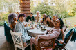 © Maskot - Portrait of happy friends from LGBTQ community sitting at dining table during dinner party in back yard