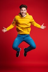 happy man jumping in yellow shirt on a red background