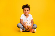 Full Length Photo Of Cute Positive Little Boy Dressed White T-shirt Holding Money Piggy Box Isolated Yellow Color Background