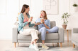 © Pixel-Shot - Female friends with cups of coffee sitting on sofa at home