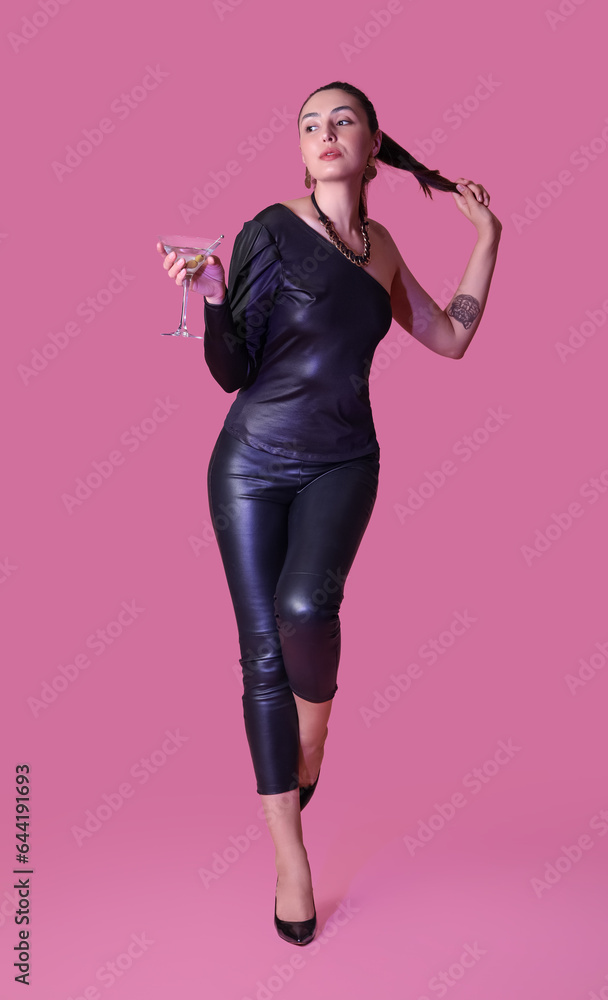 Beautiful woman with martini on pink background