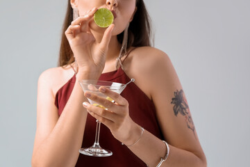 Wall Mural - Beautiful woman with martini and lime on light background, closeup