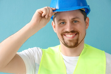 Canvas Print - Male builder in hardhat on blue background, closeup