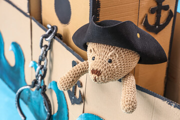 Poster - Pirate cardboard ship with toy bear on blue background, closeup