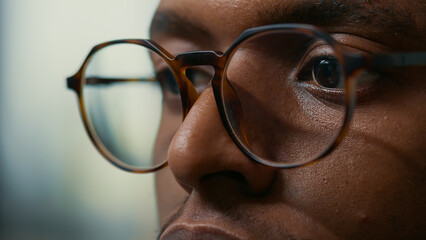 Closeup portrait of african american database developer with glasses working focused looking at computer screen while typing. Focus on moving eyes of software developer writing ai code.