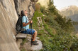© Guzel - Athletic mature man sitting by a cliff on a mountain trail over an impressive view of the valley
