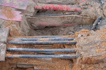 Wall Mural - red corrugated pipe are buried underground on the street. underground electric cable infrastructure installation. Construction site with A lot of communication Cables