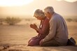© Nicols - Emotive image of a standing couple aged 65 praying in the desert