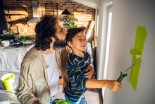 Young Father And Son Renovating And Painting Walls At Home