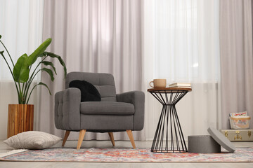 Poster - Stylish gray armchair and small table in living room. Interior design