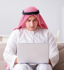 Wall Mural - Young arab businessman working with laptop on sofa