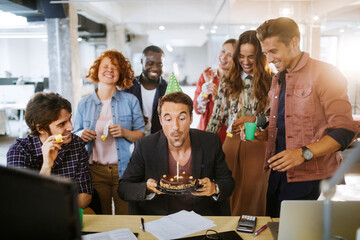 Wall Mural - Young and diverse group of people celebrating a surprise birthday party in the office of a startup company