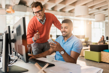 Young diverse coworkers using a smartphone in a startup company office