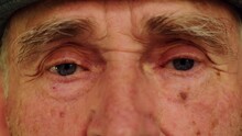 Tired Eyes Of A Senior Caucasian Man. Close-up Of An Elderly Wrinkled Man's Eyes. Wise Look Of An Old Grandfather. Grandparents Day Concept.
