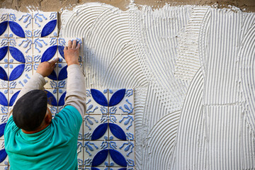 A builder, tiler placing 3 dimension azulejos on adhesive cement, exterior wall, Lagos, Algarve, Portugal, Europe