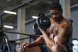 © Westend61 - Young shirtless man strengthening biceps with dumbbell in gym
