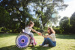 © Westend61 - Mother holding hand of daughter sitting in wheelchair on sunny day