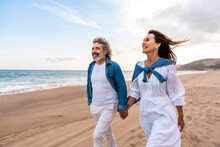 Happy Senior Couple Holding Hands Walking At Beach