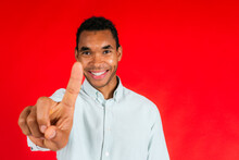 Smiling Man Pointing With Index Finger Against Red Background