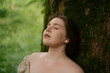 © Westend61 - Serene woman leaning on tree in garden
