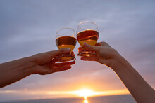 Hands Of Girlfriend And Boyfriend Toasting Wineglasses At Sunset