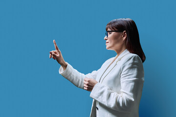 Business woman touching with finger on virtual screen, blue background