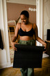 © Maskot - Smiling young woman with exercise mat standing at home