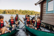 © Maskot - Kids holding oars while sitting in kayaks with counselors on lake at summer camp